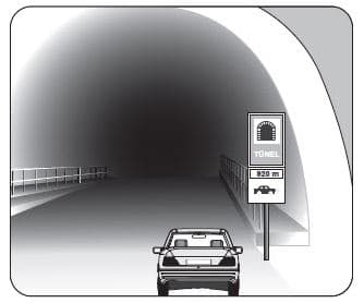 Şekildeki gibi yeterince aydınlatılmamış tünele giriş yapan aracın sürücüsü, aşağıdakilerden hangisini yapmak zorundadır?